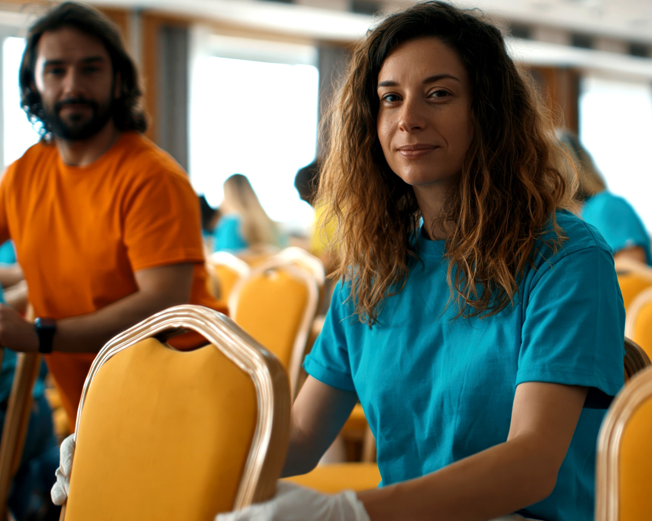 Eine engagierte Helferin schaut freundlich in die Kamera, im Hintergrund weitere Freiwillige. Symbolbild für Teamarbeit und ehrenamtliches Engagement in sozialen Vereinen und Non-Profit-Organisationen | HAGENLOCHER PR