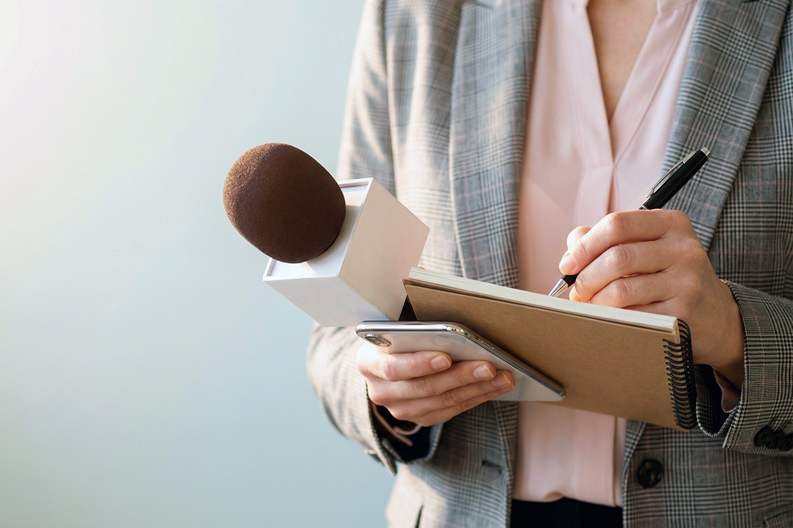 Journalistin mit Mikrofon macht sich auf einem Block Notizen