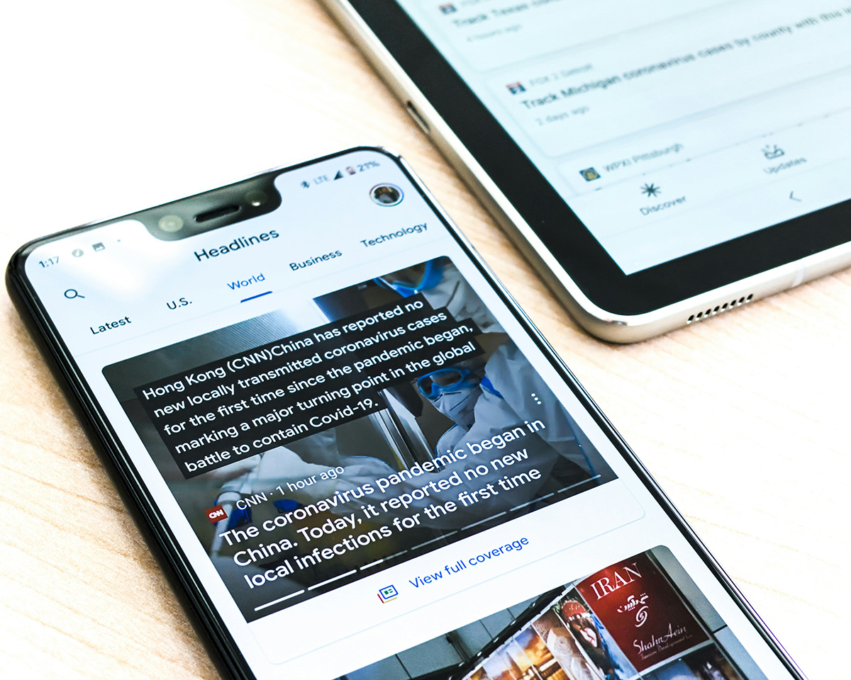 Nahaufnahme eines Smartphones und eines Tablets auf einer hellen Holzoberfläche, die digitale Medieninhalte, Nachrichten-Feeds und Artikelanzeigen darstellen | Native Advertising - Advertorials | HAGENLOCHER PR | © Foto von Obi auf Unsplash